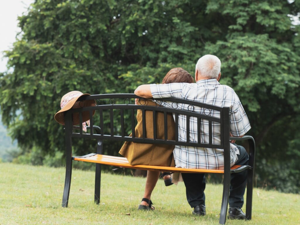 A senior citizen couple sits on a bench overlooking water in Sarasota Florida as they are relieved to have just sold their home to Tranquil Transition Partners and were fronted the equity to make their move to senior living care.
