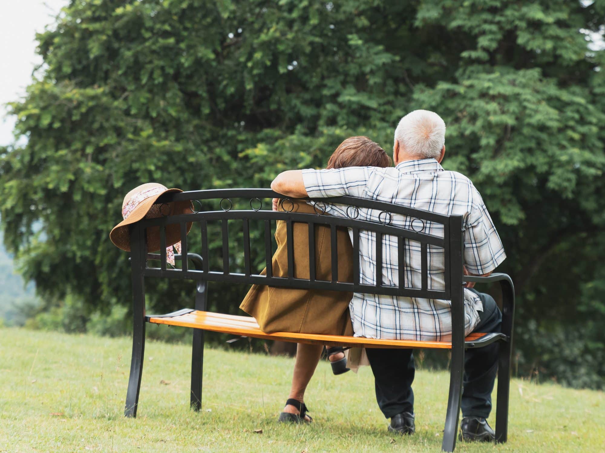A senior citizen couple sits on a bench overlooking water in Sarasota Florida as they are relieved to have just sold their home to Tranquil Transition Partners and were fronted the equity to make their move to senior living care.